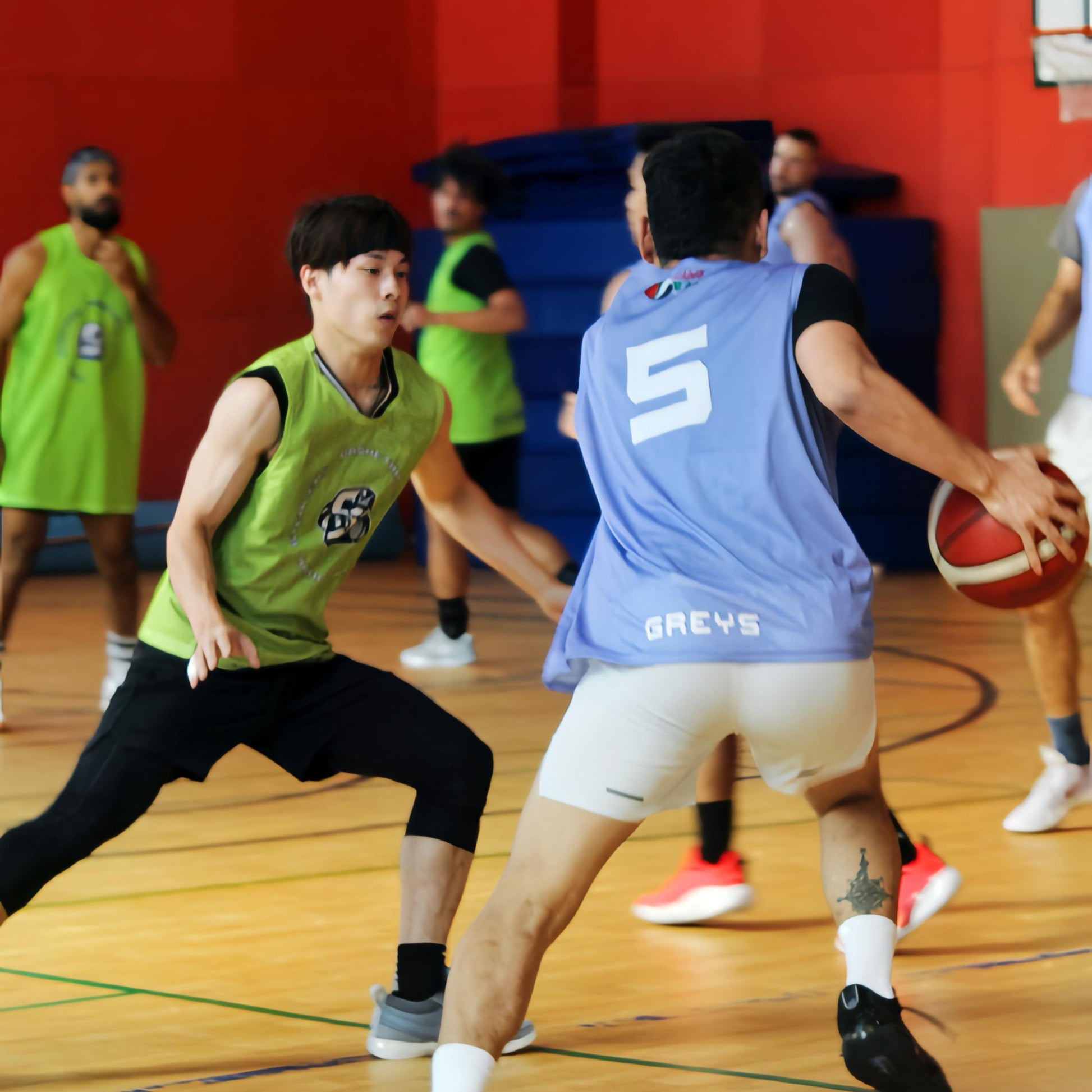 Basketball game in progress with players on a court against a red wall. Dubai Stealers Basketball Pickup Game Run.